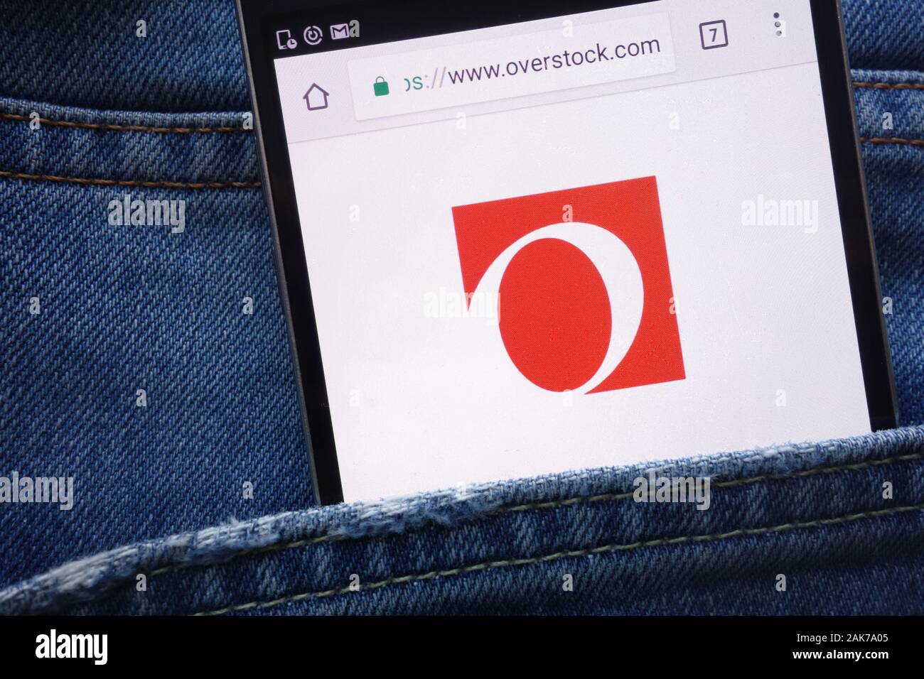 Overstock website displayed on smartphone hidden in jeans pocket Stock Photo