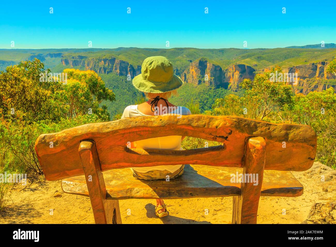Tourist woman with hat relaxing on rustic wooden bench and enjoying