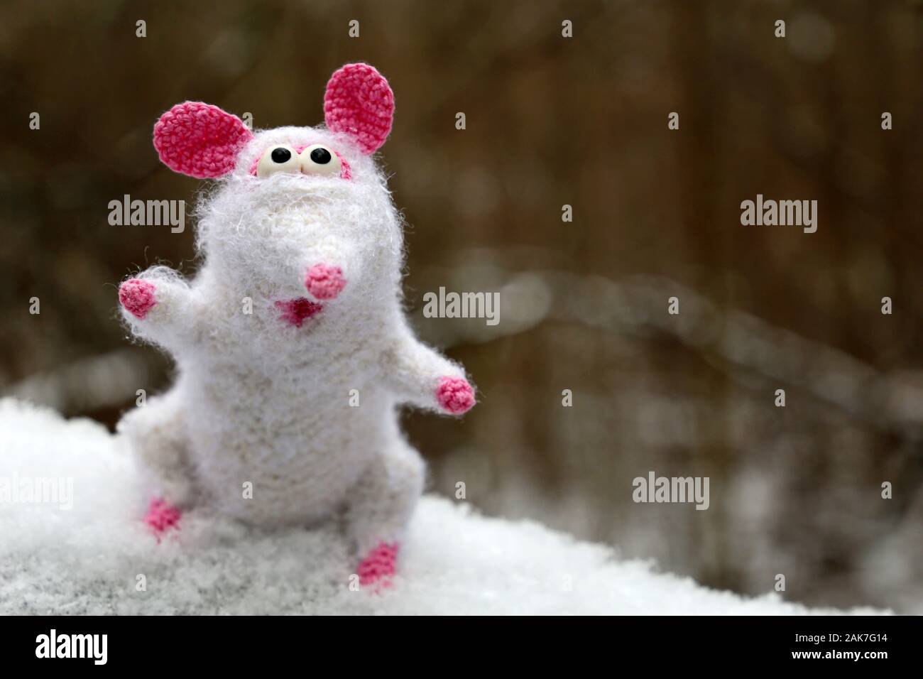 White knitted toy rat on the snow in winter forest, New Year card. Chinese Year of Rat, Zodiac symbol 2020 Stock Photo