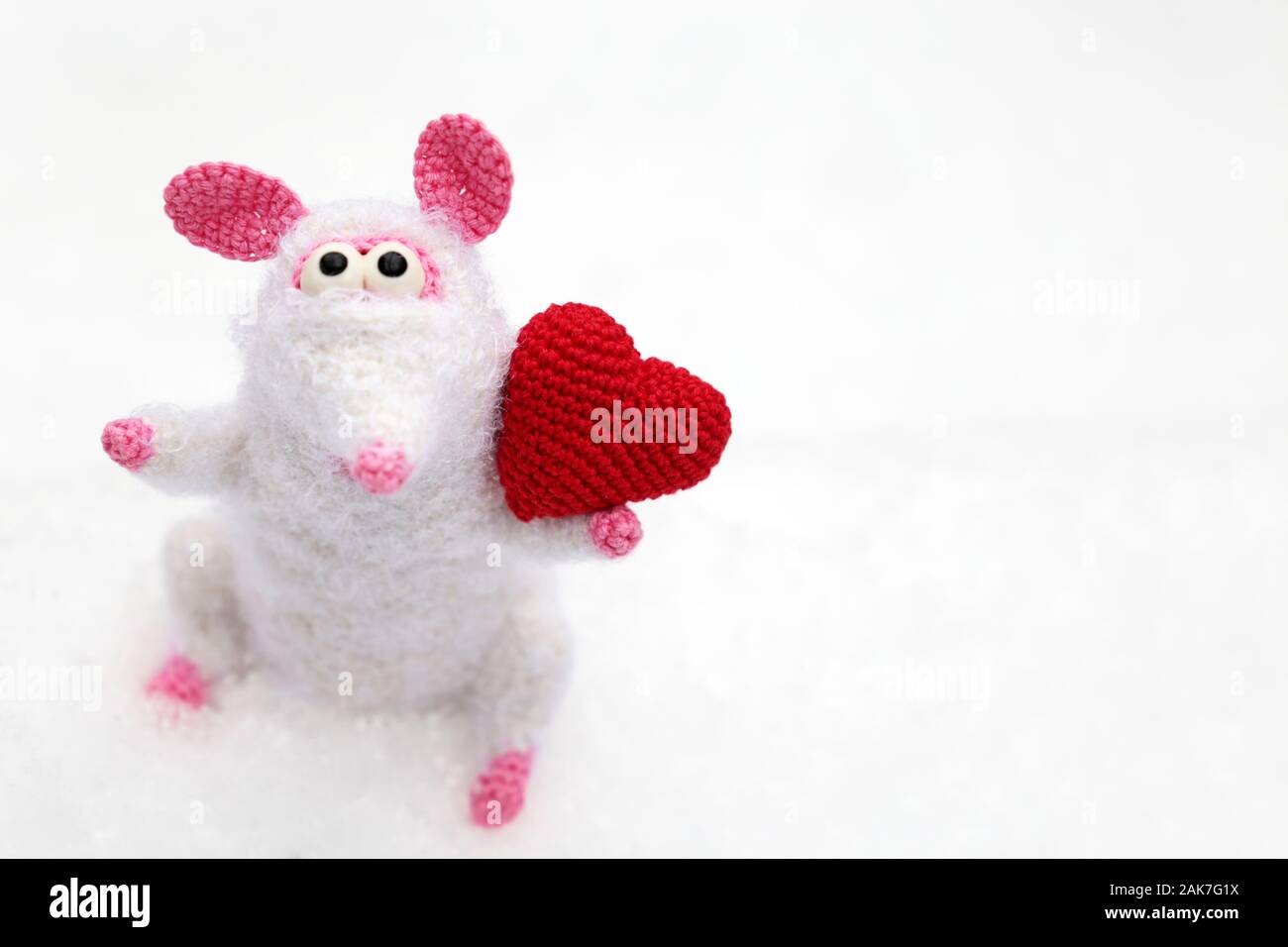 White knitted toy rat with red heart on the snow in winter park, selective focus. New Year and Valentine card, Chinese Year of Rat, Zodiac symbol 2020 Stock Photo