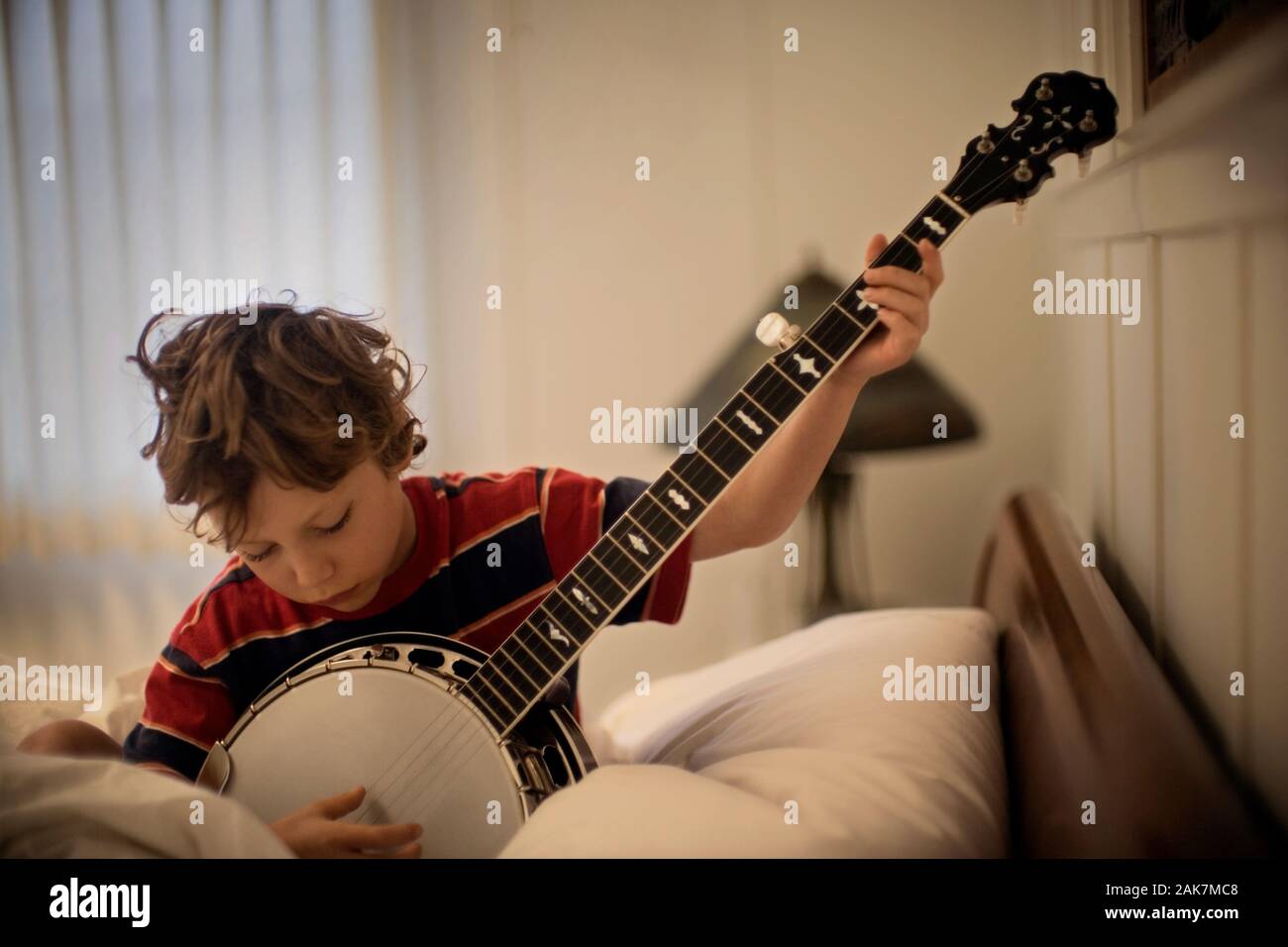 boy playing banjo in bed Stock Photo Alamy
