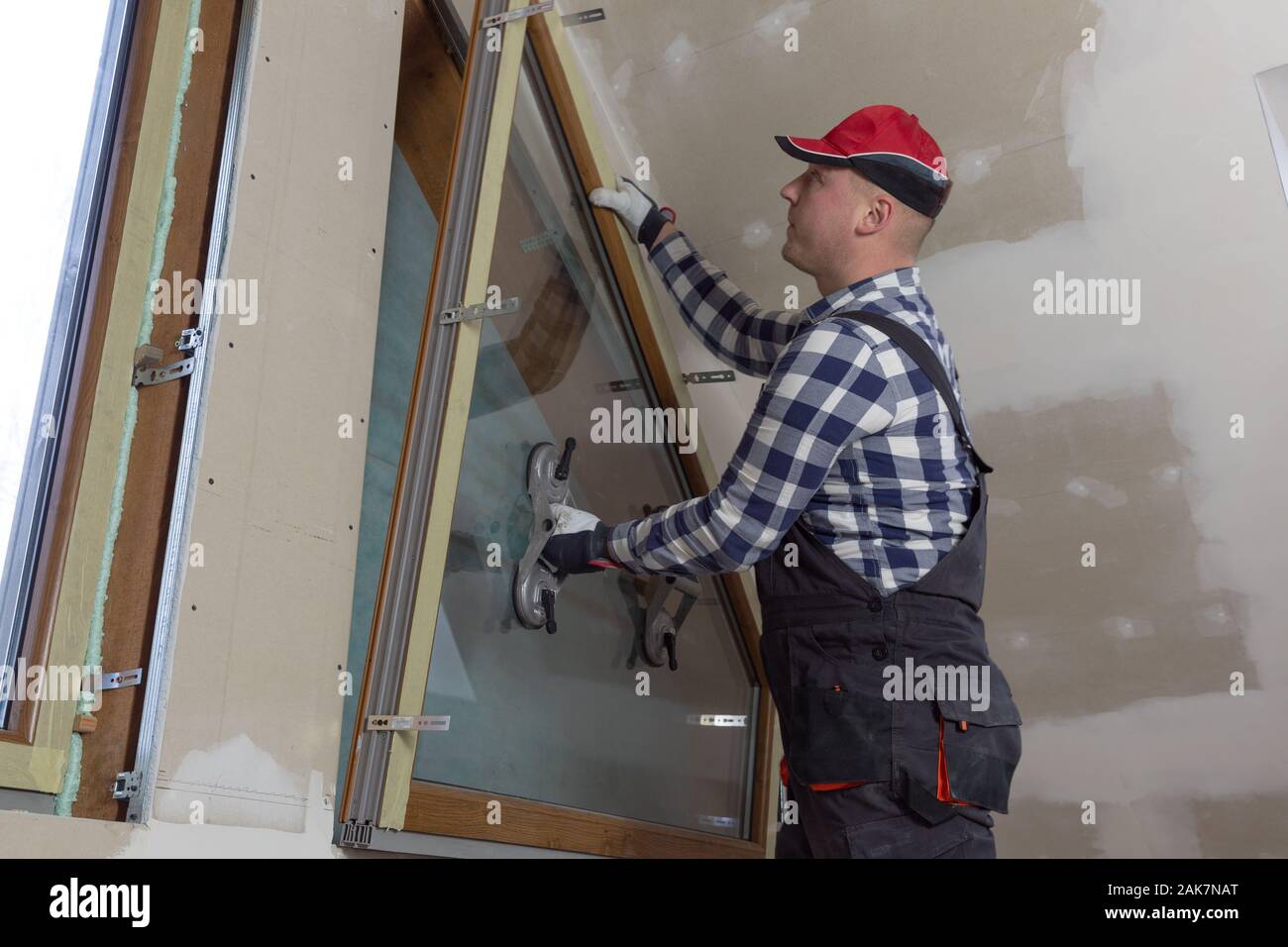 Handyman, construction man installing PVC window in a new insulated and filled dry wall attic. Stock Photo