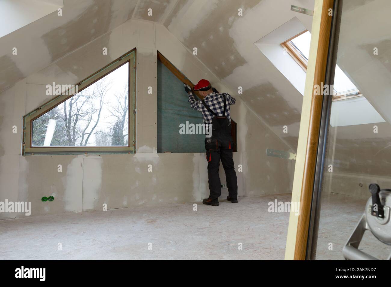 Handyman, construction man installing PVC window in a new insulated and filled dry wall attic. Stock Photo