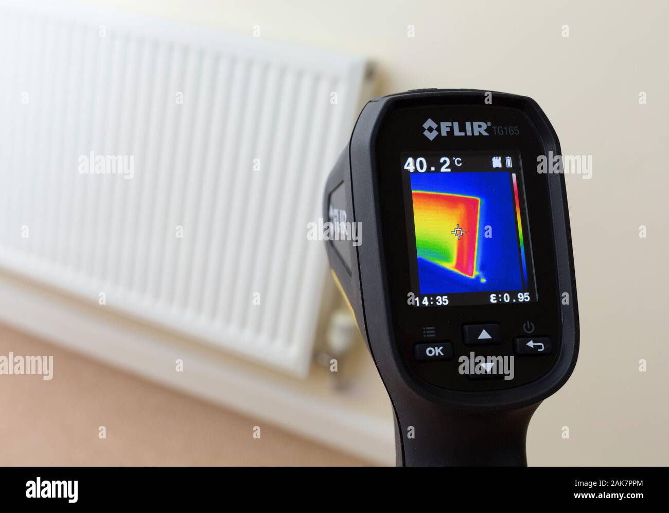 Thermal image camera being used to check temperature of domestic heating radiator in home Stock Photo