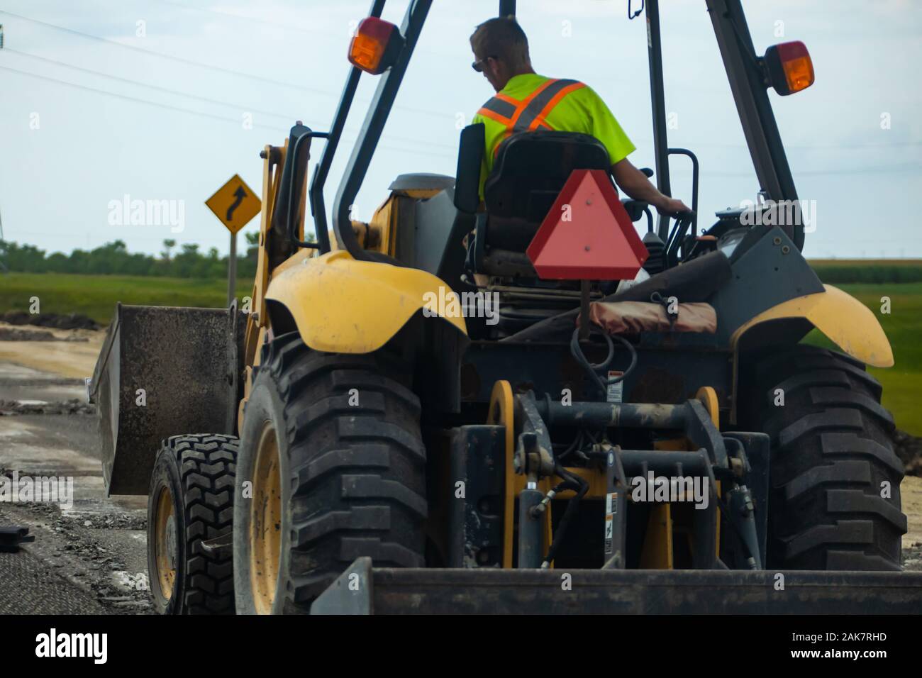 A rear view of a large tractor equipped with a front bucket, known as a