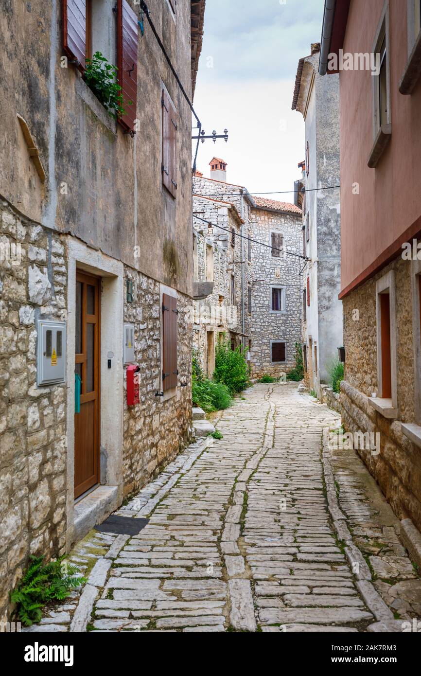A narrow paved alleyway between old buildings in the historic old town in Bale, a small hill town on Mont Perin in Istria County, Croatia Stock Photo