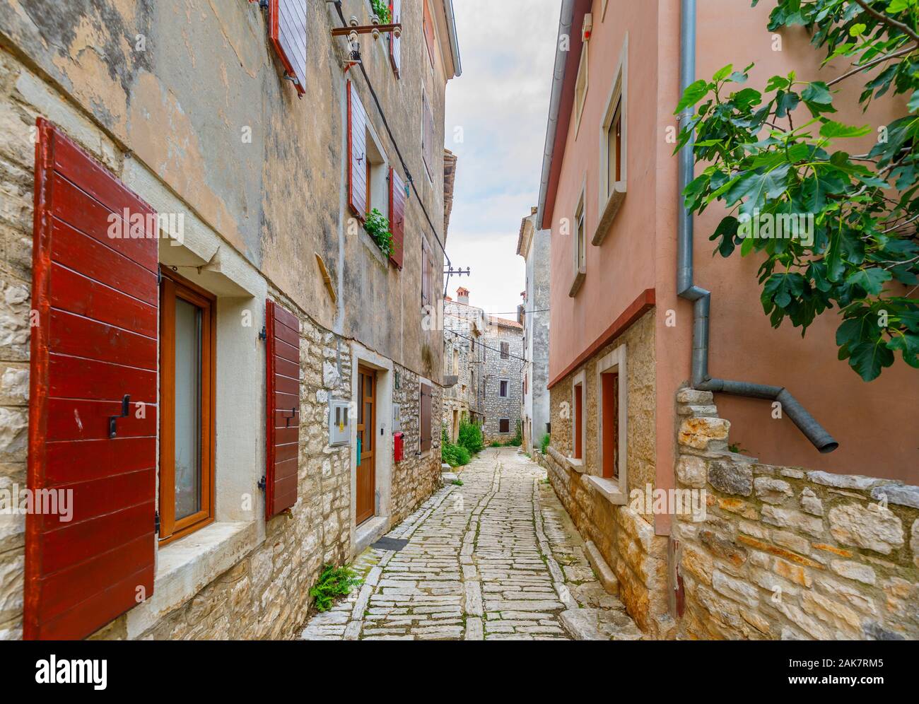 A narrow paved alleyway between old buildings in the historic old town in Bale, a small hill town on Mont Perin in Istria County, Croatia Stock Photo