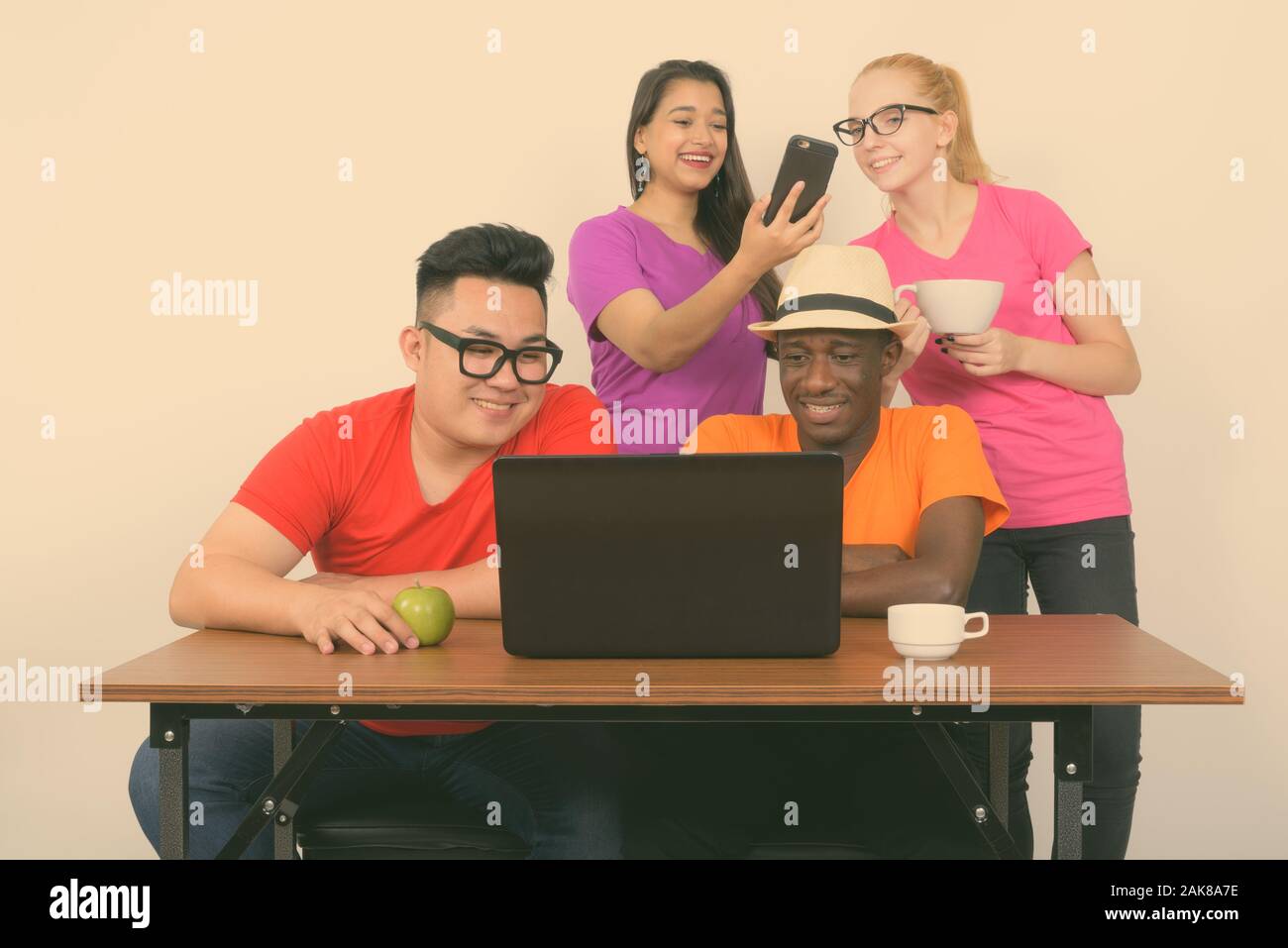 Diverse multi ethnic group of happy friends working with laptop and phone together Stock Photo