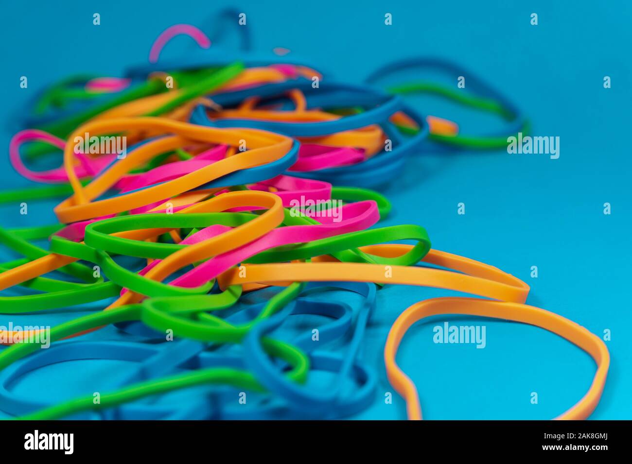 Pile of colorful rubber bands over blue background Stock Photo - Alamy