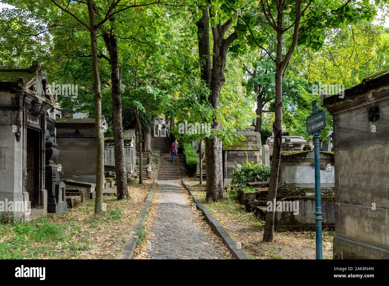 Paris, France: People walking in an alley with Trees and Graves in Pere Lachaise Cemetery on a sunny day of september. Stock Photo