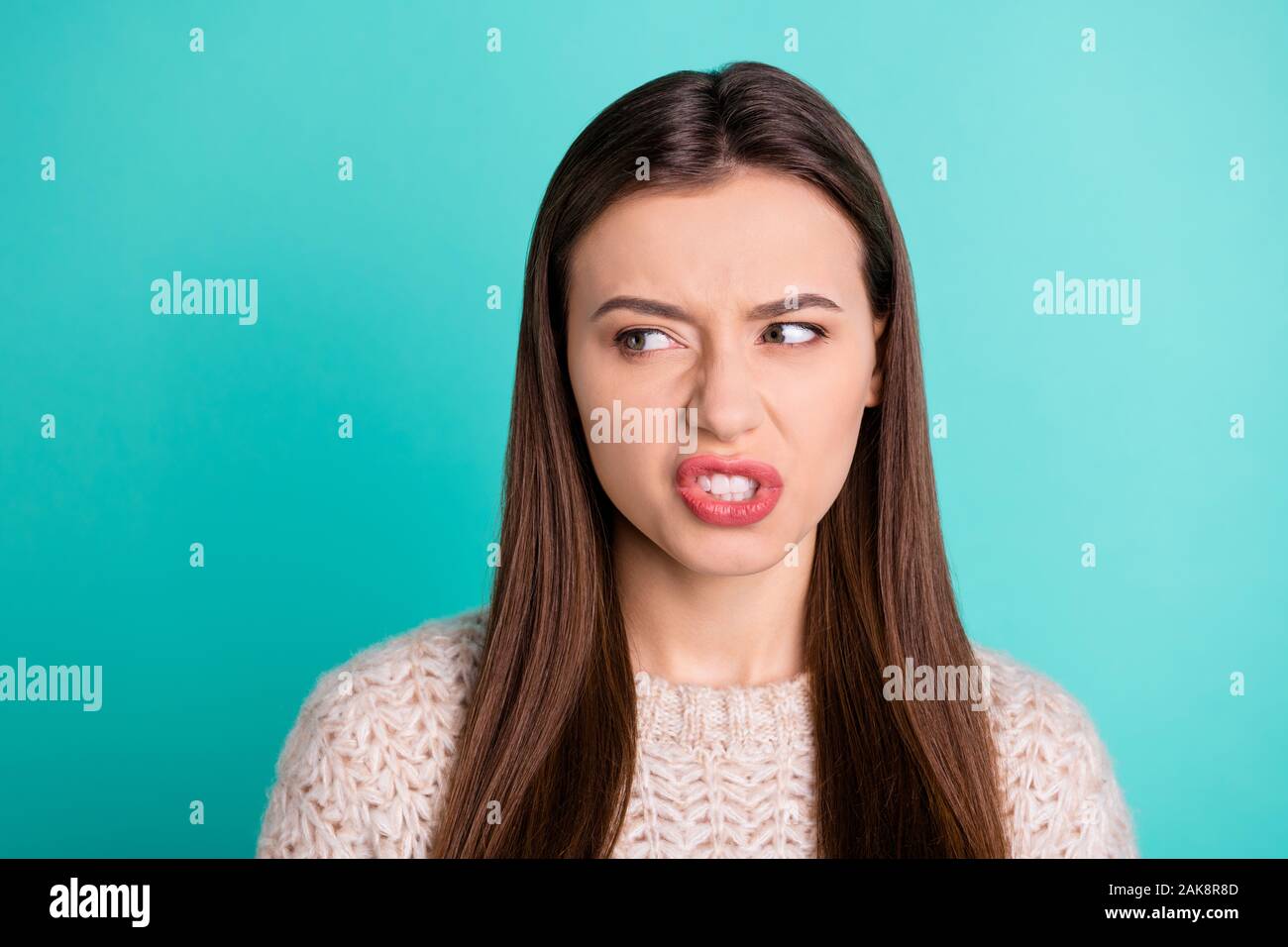 Close up photo of evil angry furious bothered girlfriend looking at someone she is envious of wearing pullover isolated over turquoise color vibrant Stock Photo