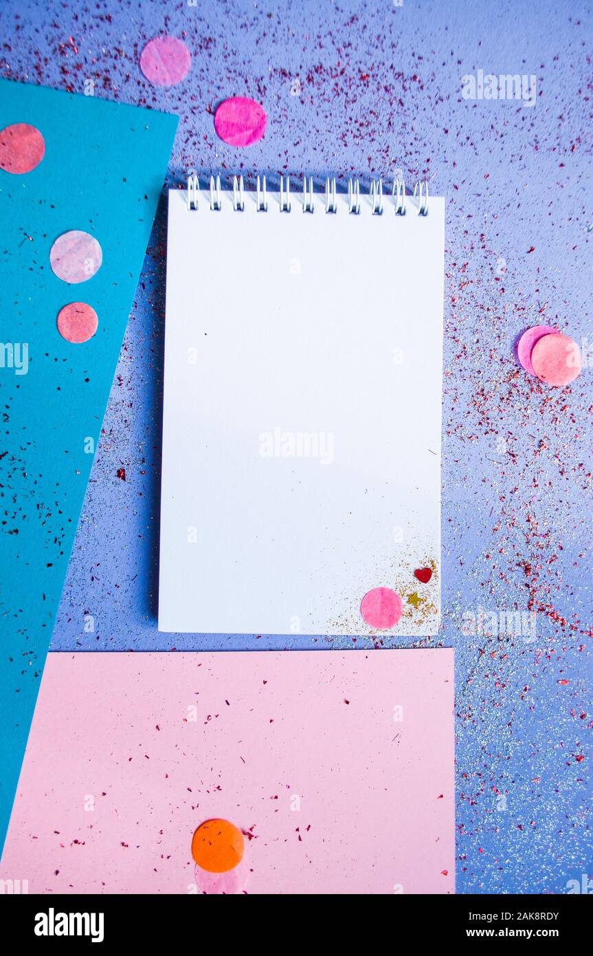Colorful confetti, sparkles and notebook with wish list on bright