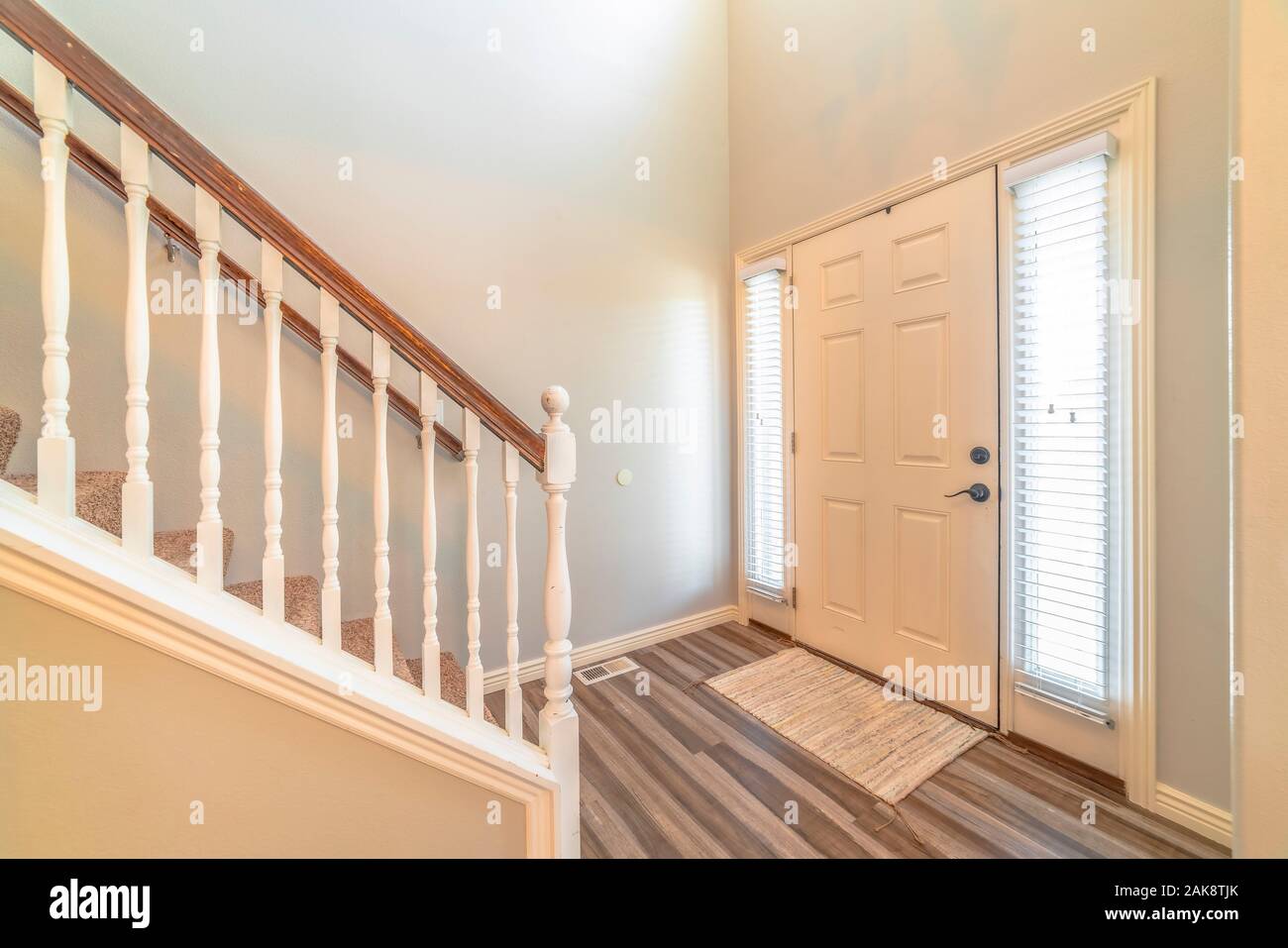 Home interior with stairs in front of the white front door flanked by  sidelights Stock Photo - Alamy
