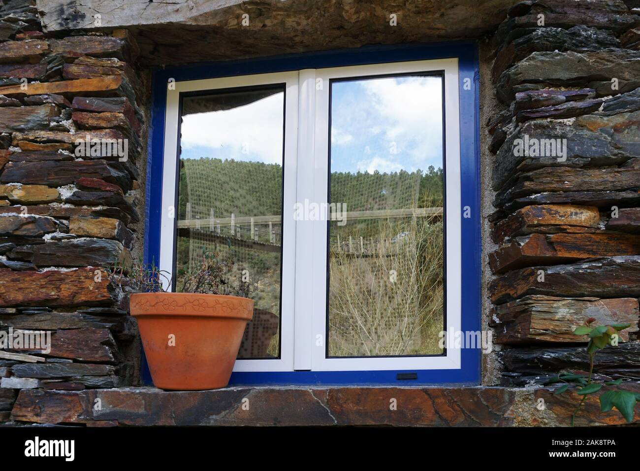 Blue window with blue trim and a rustic stone wall Stock Photo