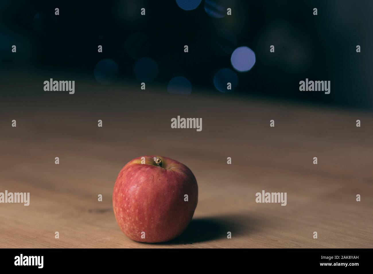 Red apple isolated on a wooden table on a dark blurry background Stock Photo