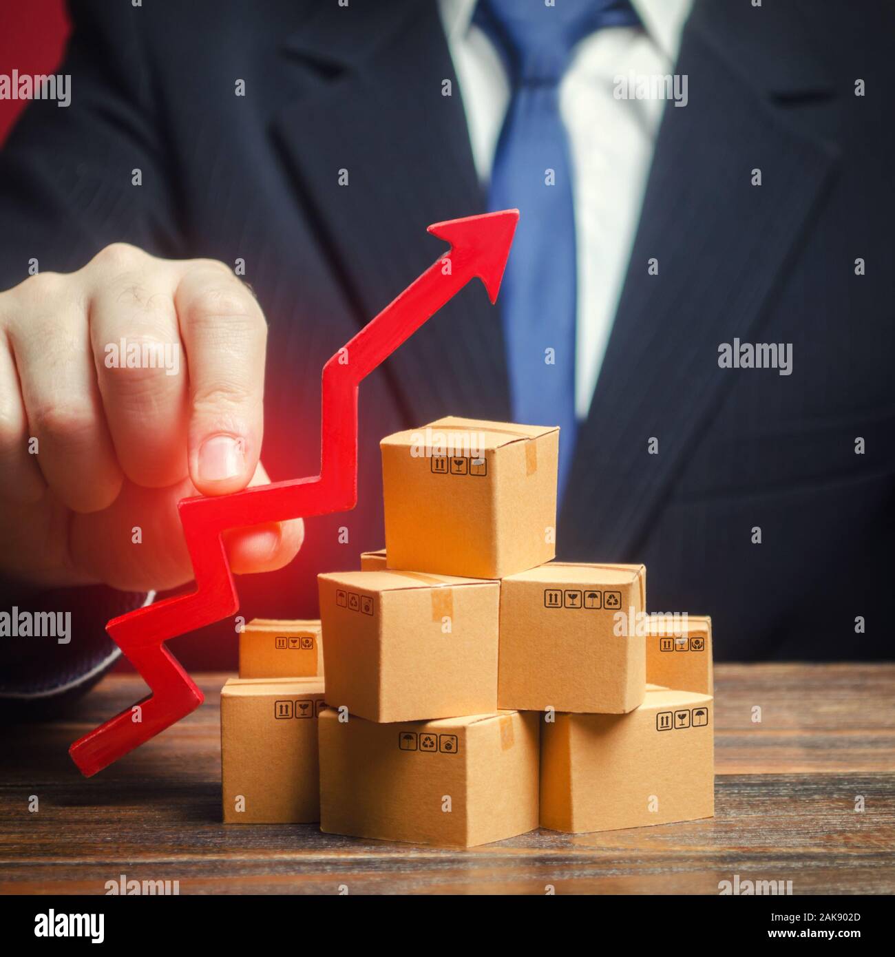 Businessman holding a red arrow up over boxes. Strategy marketing. Supply Demand. Increase sales rate, industrial goods production volumes growth , ex Stock Photo