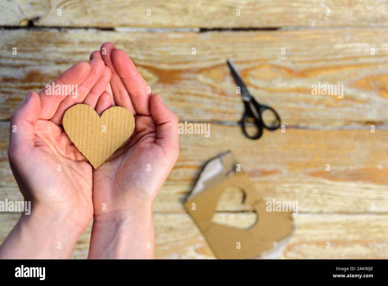 Cardboard heart in woman hands. Sustainable card for Valentines day. Reuse concept Stock Photo
