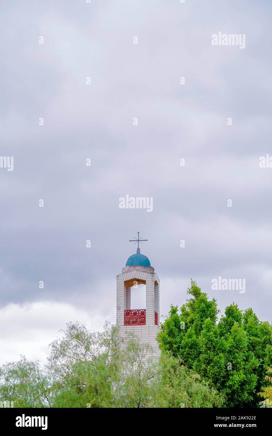Bell Tower of a church rising above green trees Stock Photo