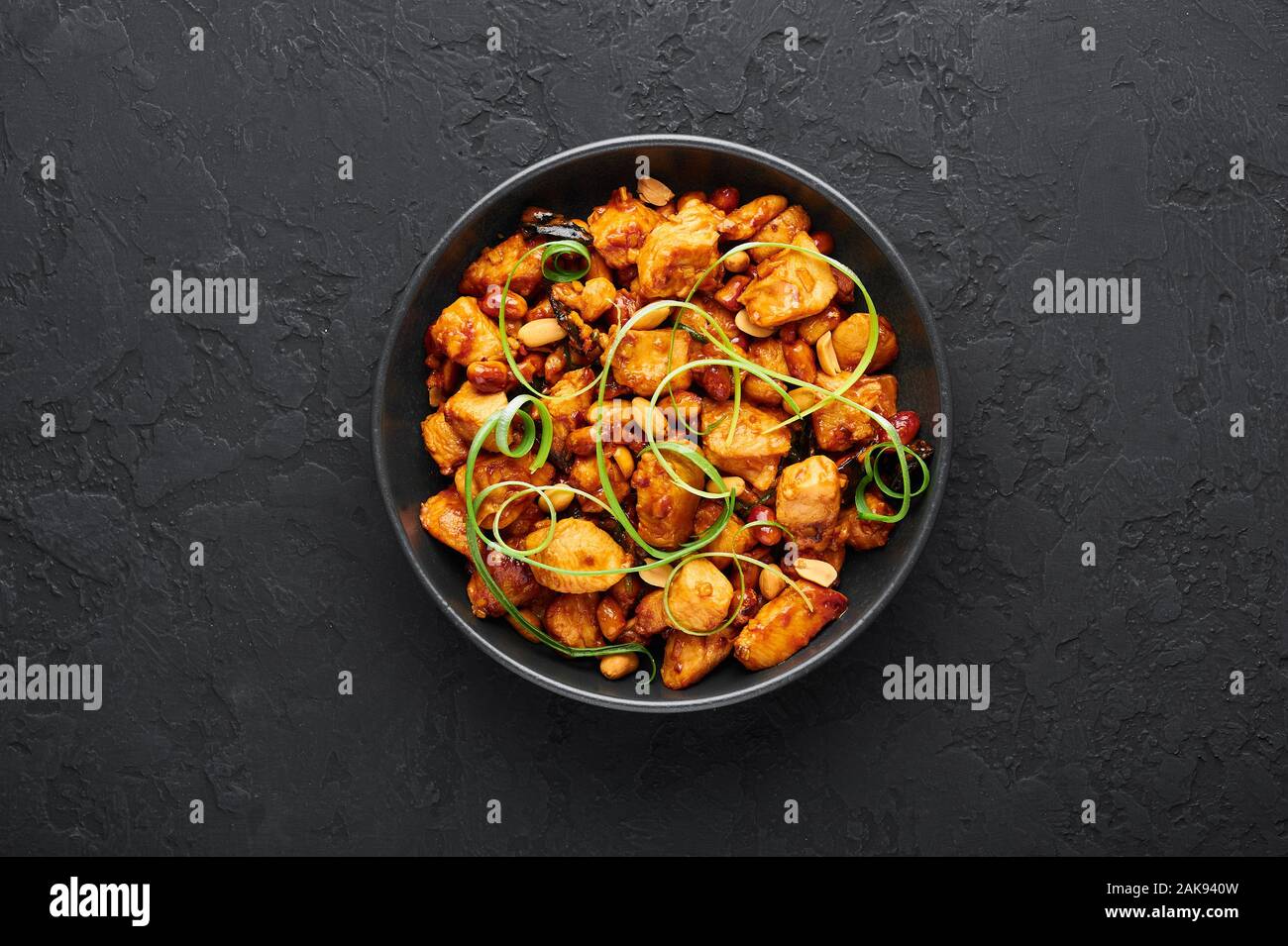 Kung Pao Chicken or Gong Bao Ji Ding at dark slate background. Sichuan Kung Pao is chinese cuisine dish with chicken meat, chilli peppers, peanuts, sa Stock Photo