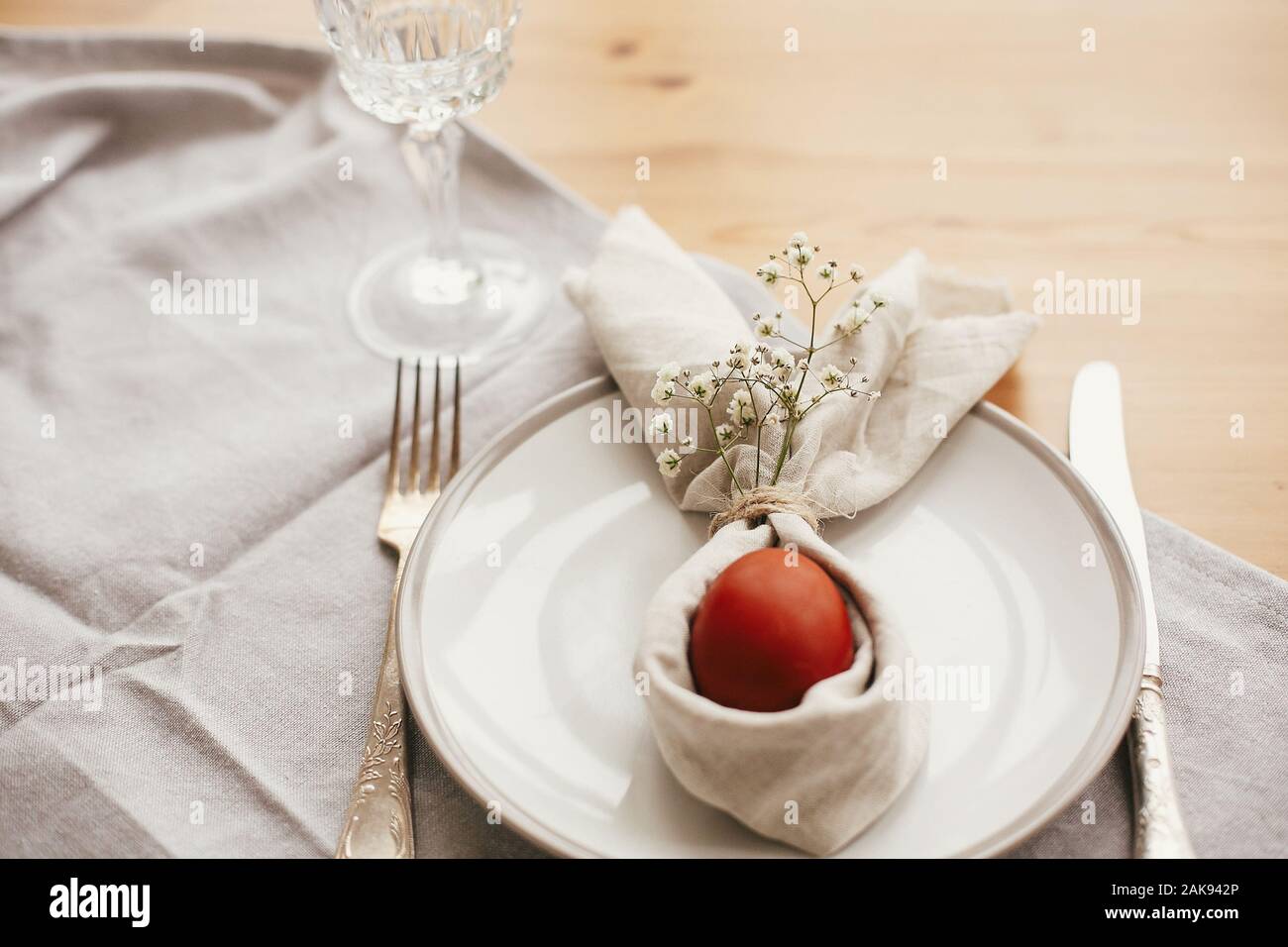 Easter table decorations. Stylish Easter brunch table setting with egg in easter bunny napkin on  table. Natural dyed easter egg on napkin with bunny Stock Photo
