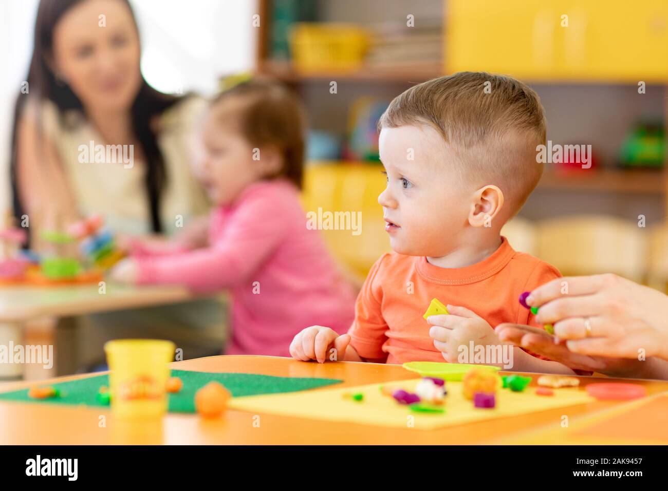 kids toddlers playing with play clay at nursery or kindergarten or daycare Stock Photo