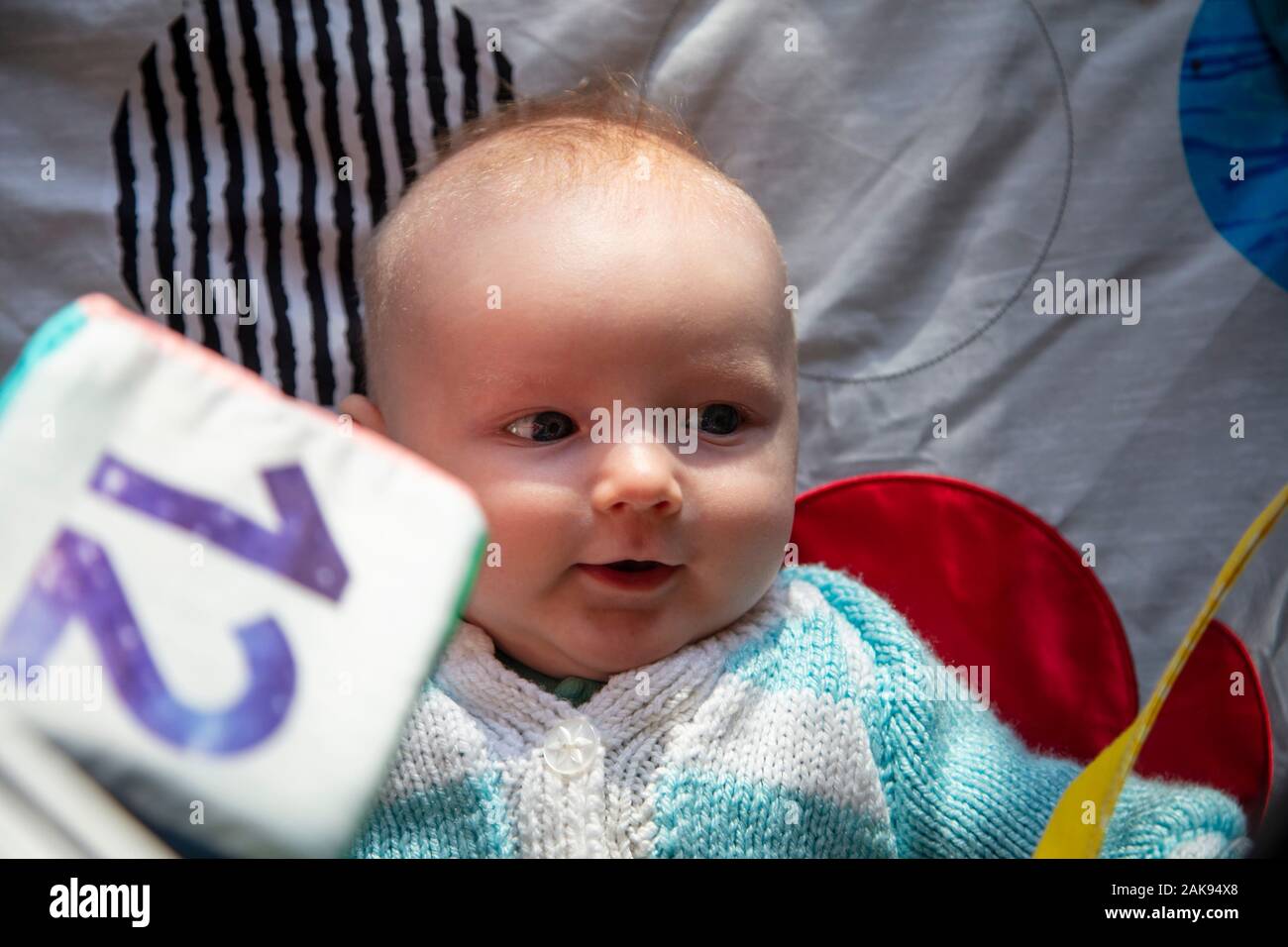 A cute young baby playing on a sensory development activity playmat Stock Photo