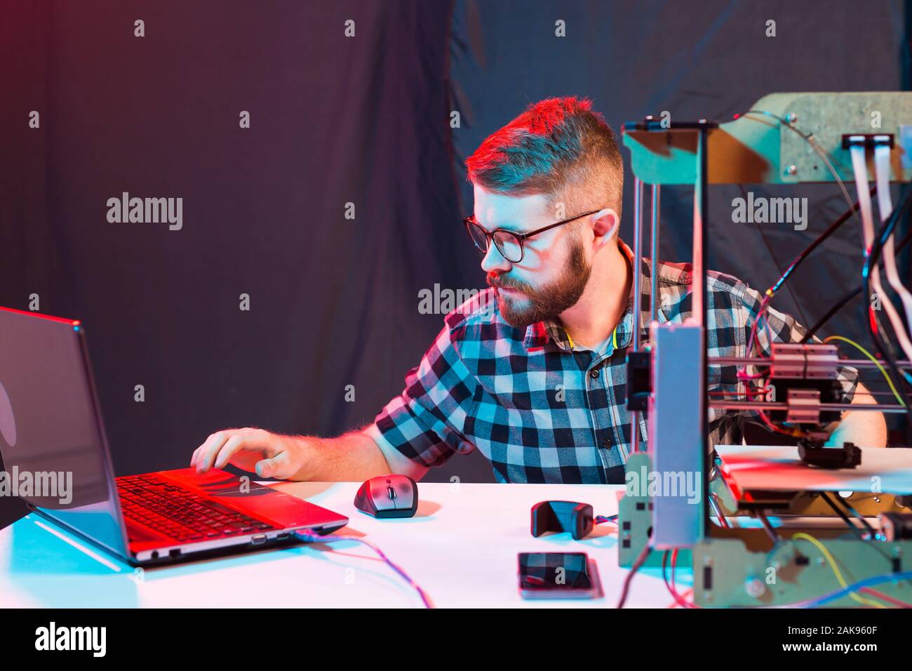 Young male designer engineer using a 3D printer in the laboratory and studying a product prototype, technology and innovation concept. Stock Photo