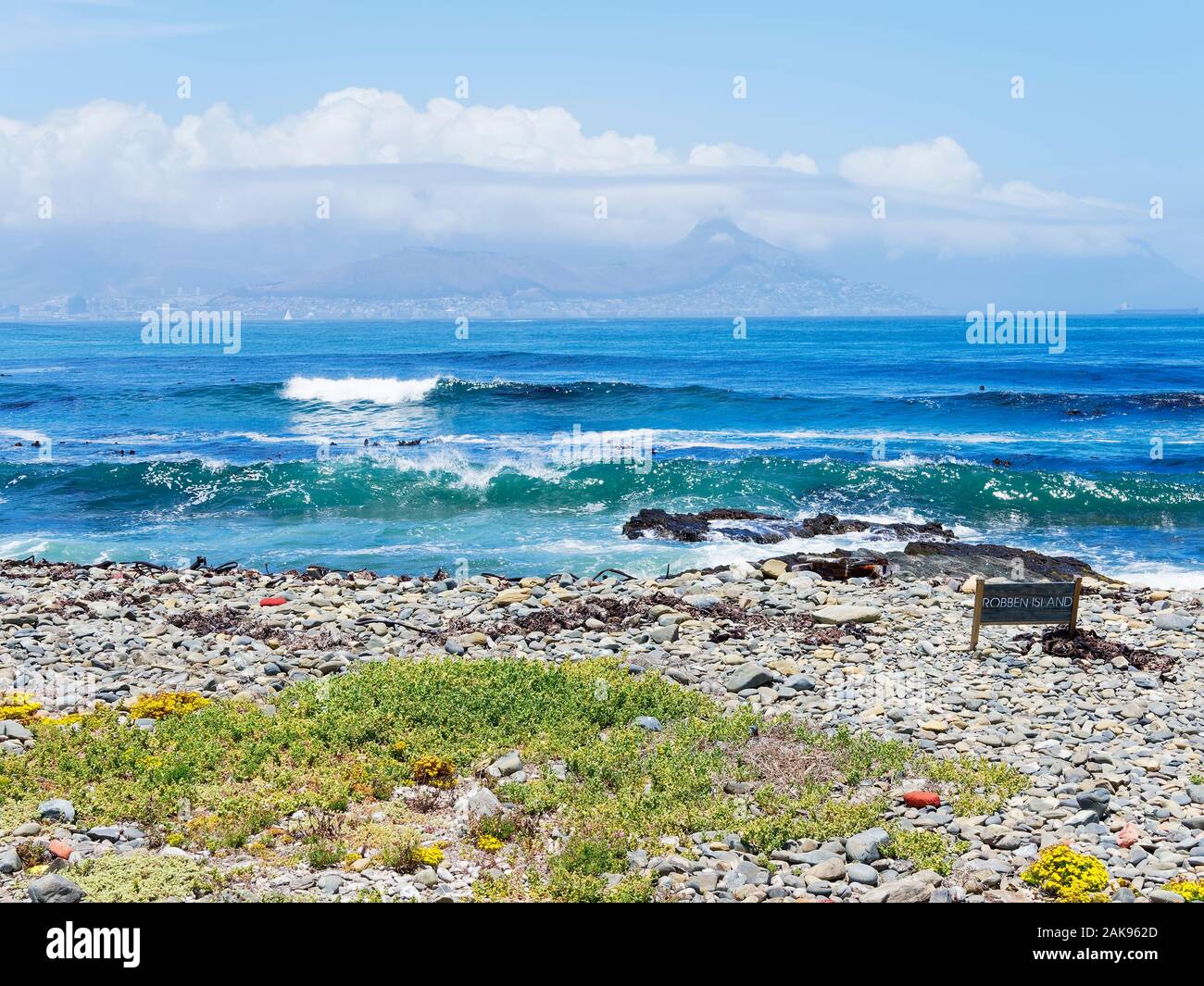 From the rocky shore of Robben Island across Table Bay to a distant, hazy, Cape Town. Stock Photo