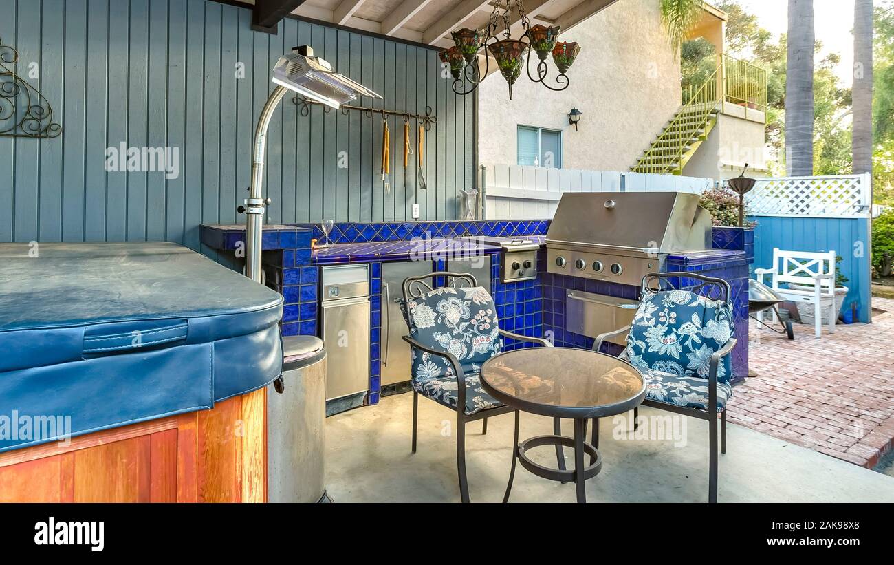 Panorama High Angle View Of A Stylish Outdoor Kitchen On A Brick Patio With A Built In Gas Barbecuerug And Dining Table With Hanging Chandelier 2AK98X8 