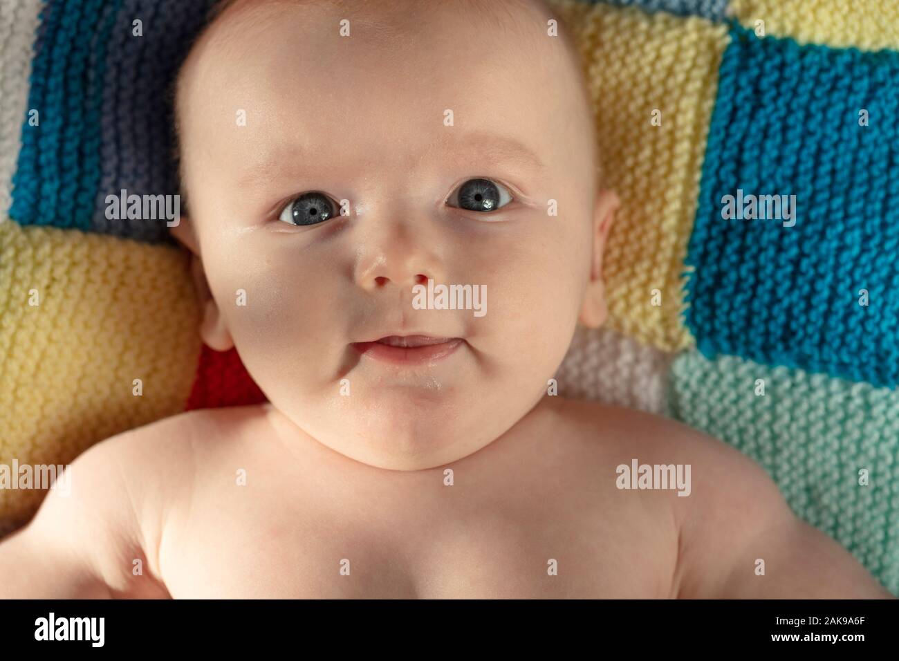 Portrait of a cute baby with blue eyes laying on a knitted balnket Stock Photo