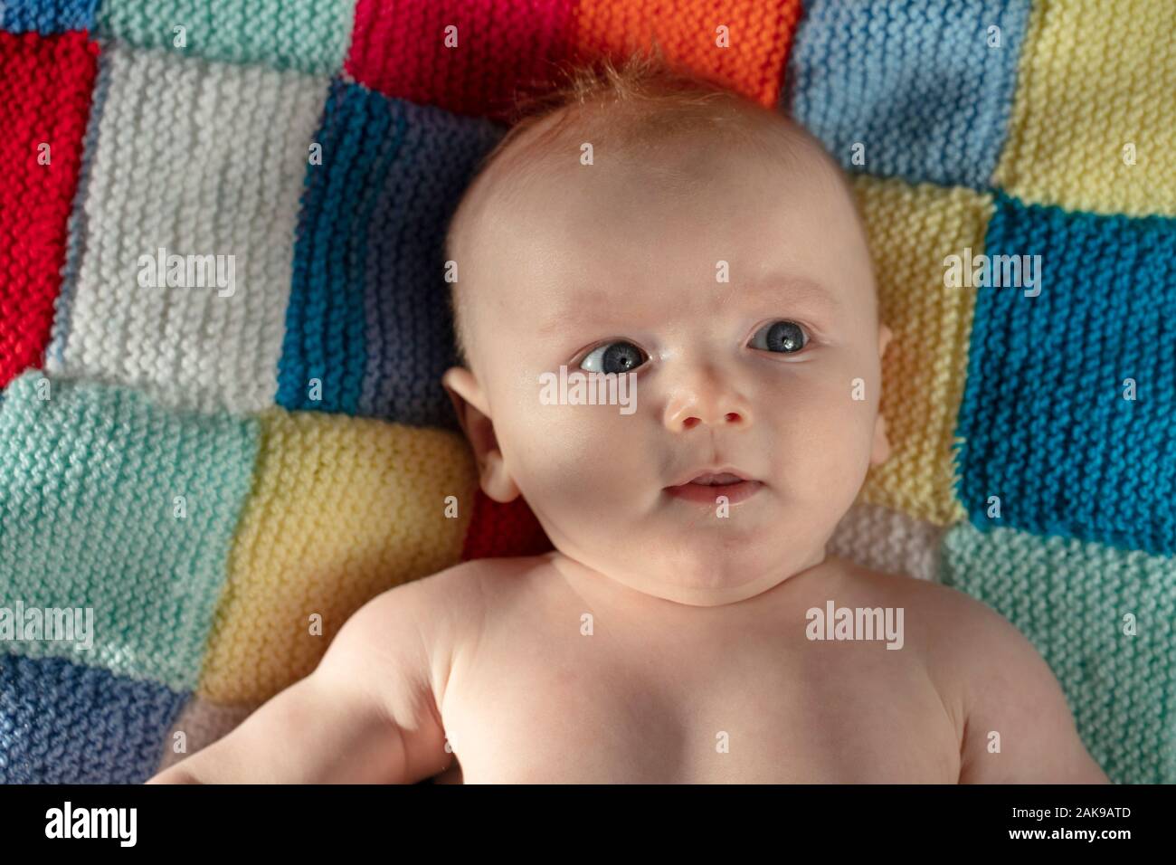 Portrait of a cute baby with blue eyes laying on a knitted balnket Stock Photo