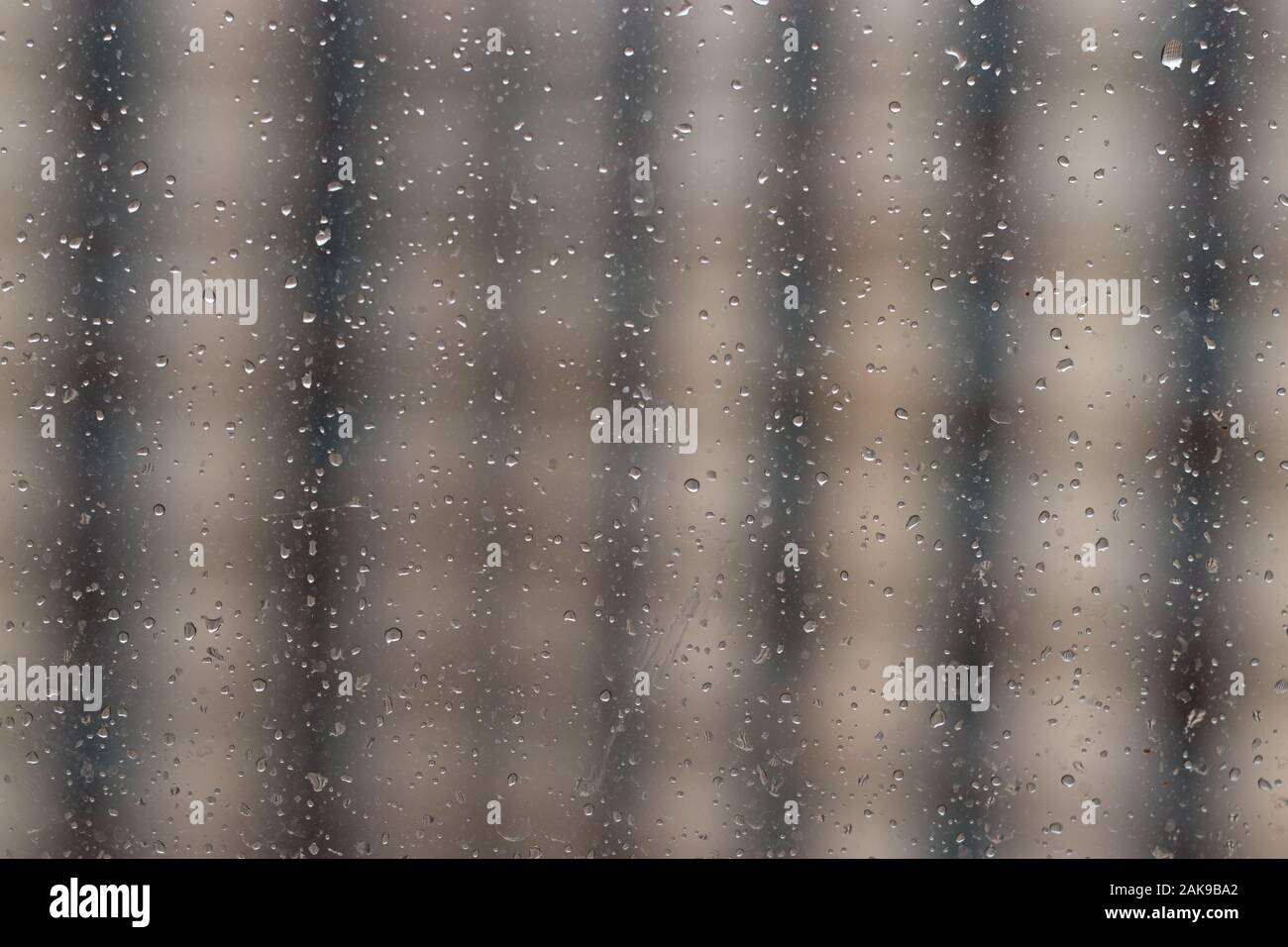 Raindrops on window glass, blurred striped background. Stock Photo