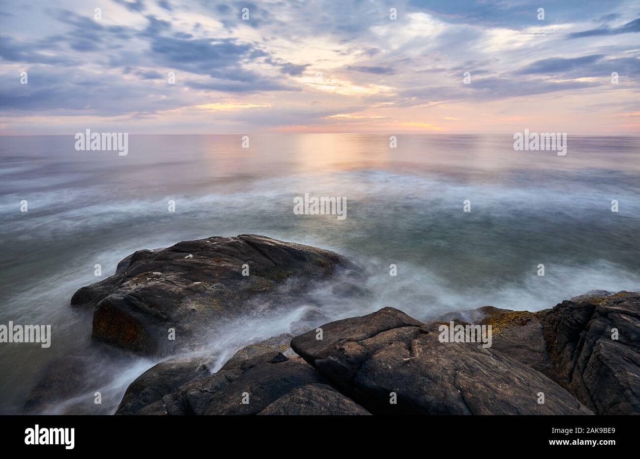 Scenic sunset over water seen from rocky shore, long time exposure, Sri Lanka West Coast. Stock Photo