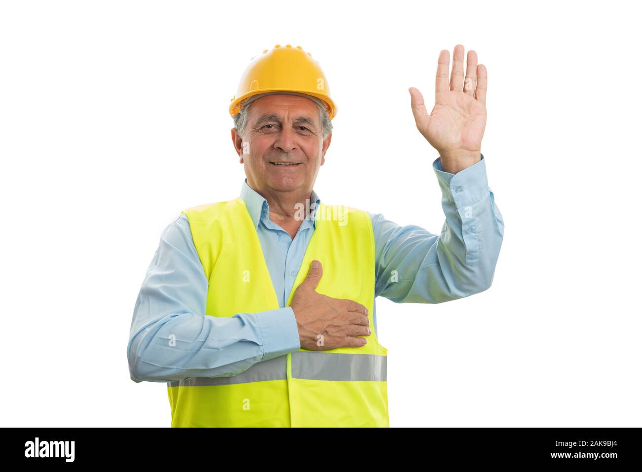 Old male builder smiling as making honest oath touching chest and holding hand up isolated on white Stock Photo