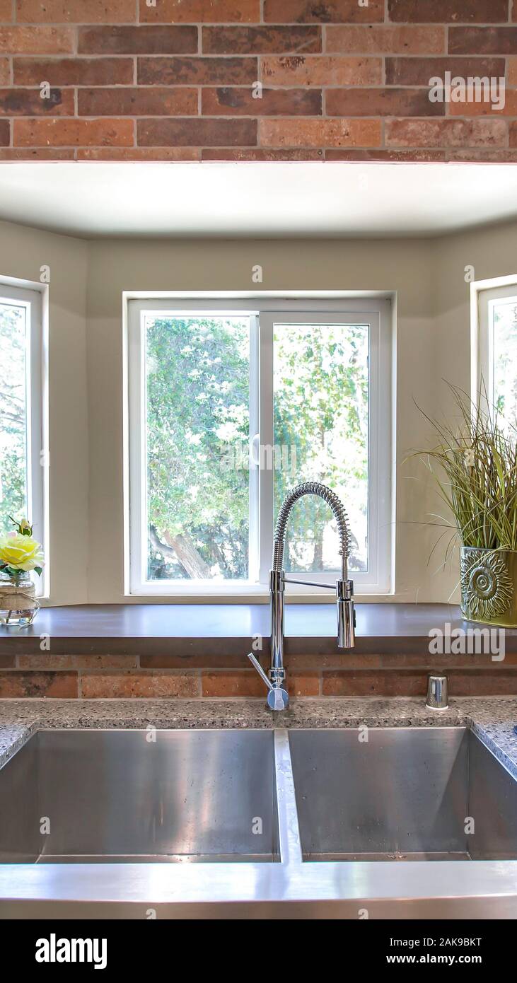 Vertical frame Kitchen sink close up with bay windows in the background
