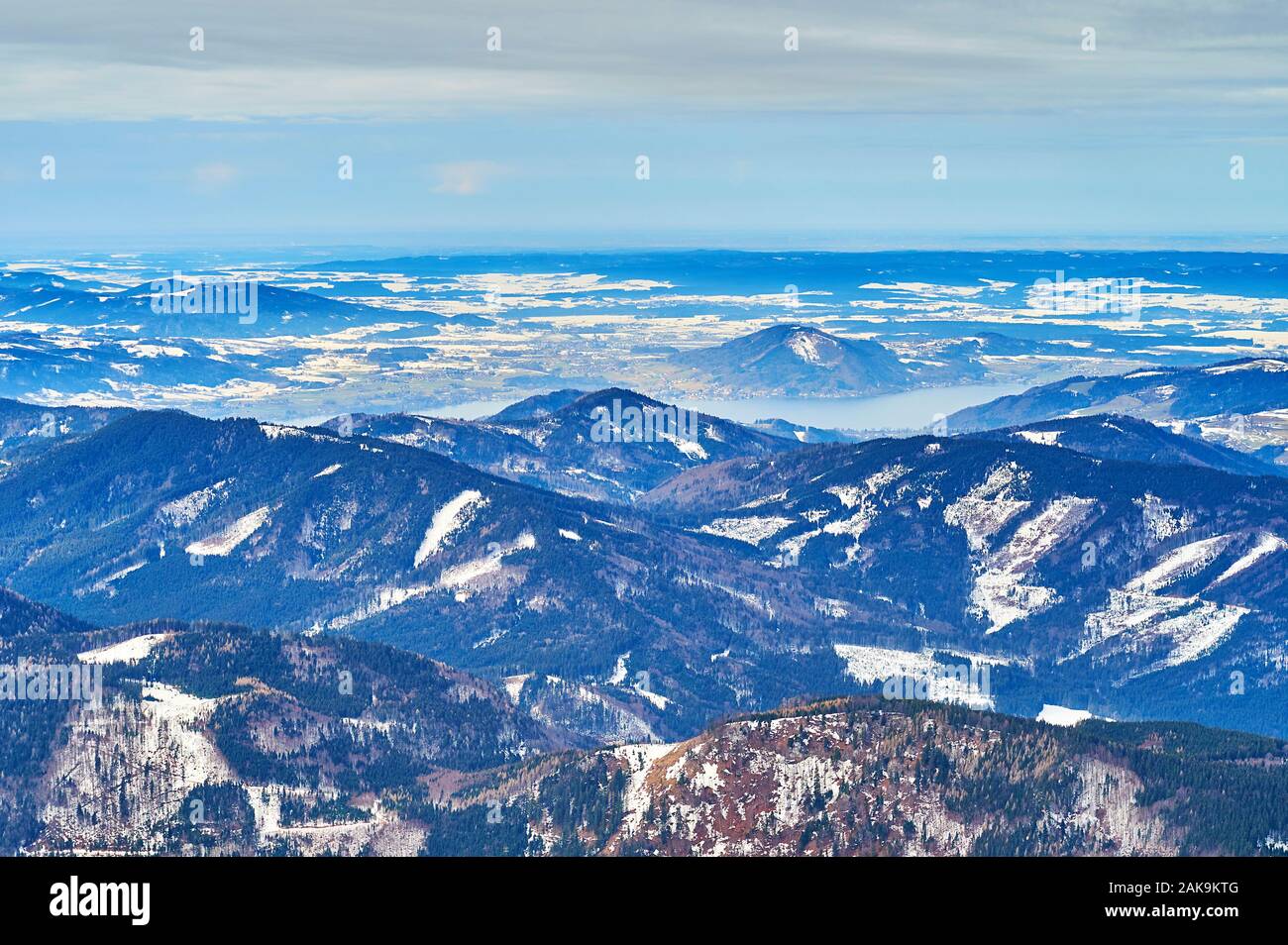 The hazy snowy landscape of Salzkammergut with Attersee lake, hidden behind the rocky slopes, seen from the top of Alberfeldkogel mount, Ebensee, Salz Stock Photo