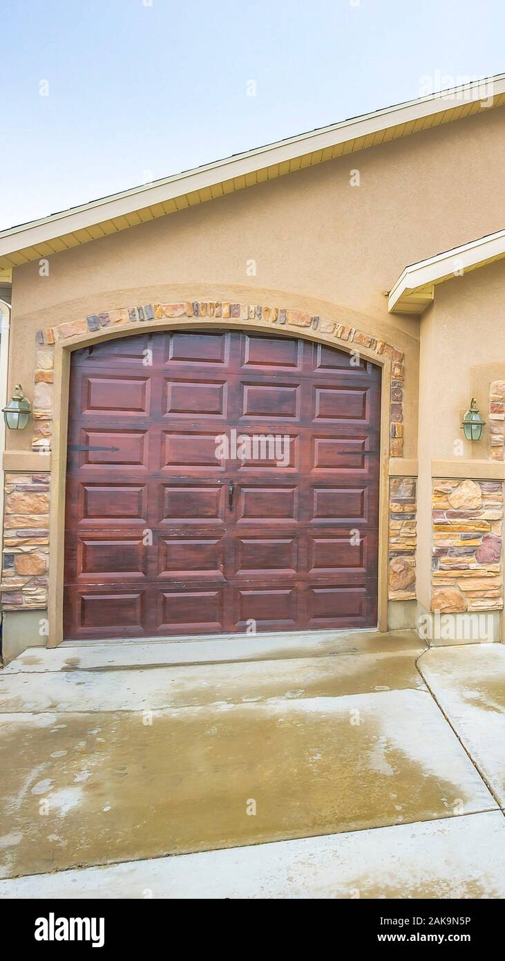 Vertical House exterior with a two car garage and concrete wall with