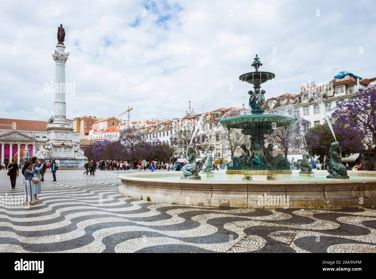 Lisbon, Portugal : Rossio square. Tourists take pictures of the South fountain. Column of Pedro IV and National theatre in background. Stock Photo