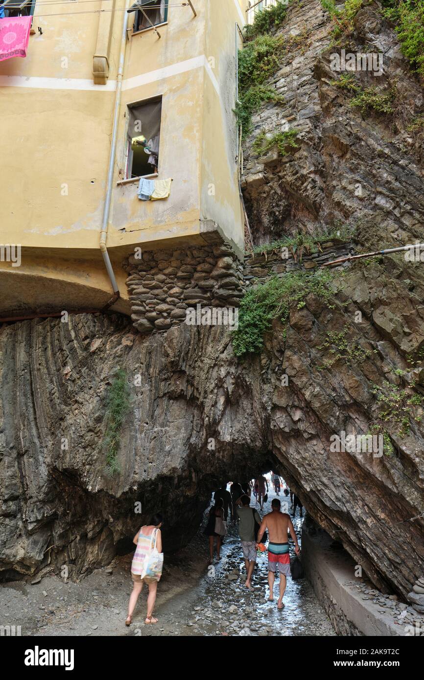 Summer tourists using the cave tunnel to the beach in the fishing village of Vernazza, Cinque Terre National Park, Liguria Italy EU Stock Photo