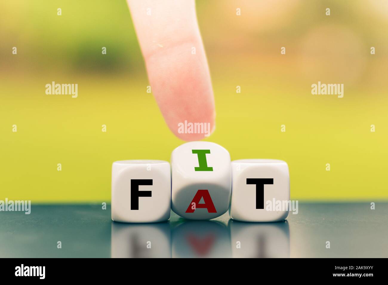 Hand turns a dice and changes the word fat to fit. Stock Photo