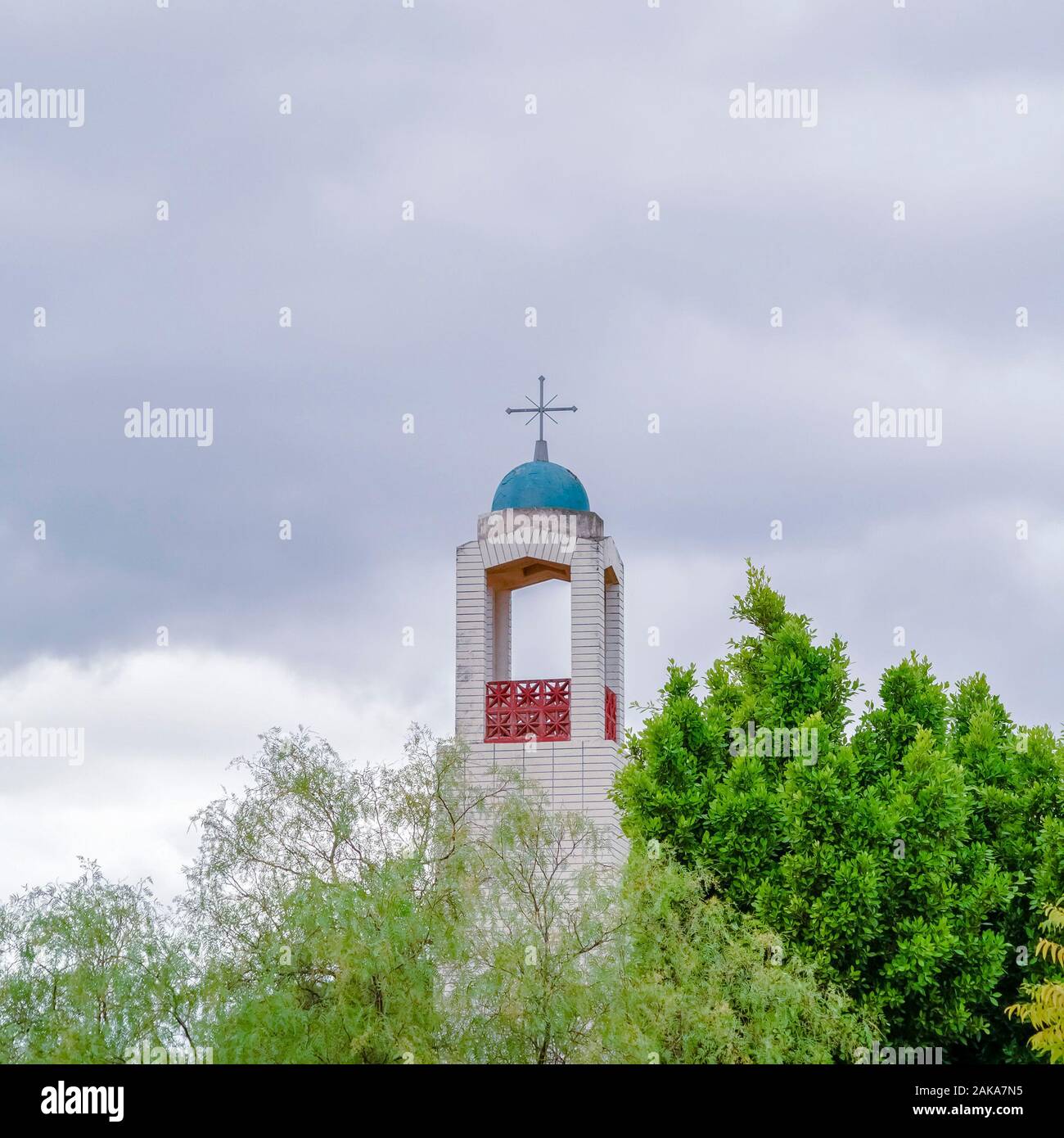 Square Bell Tower of a church rising above green trees Stock Photo