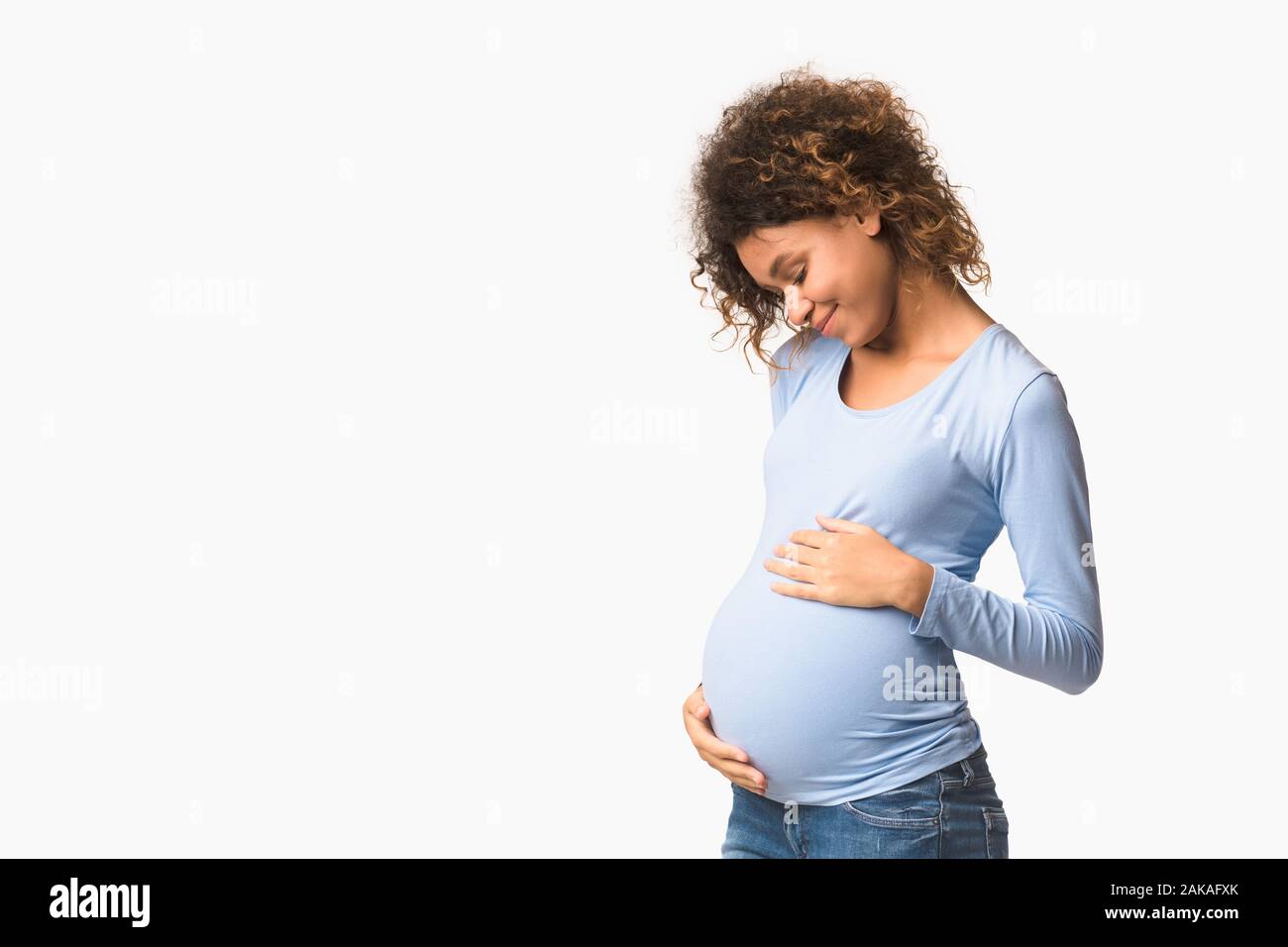 Enjoying pregnancy. Expectant woman embracing her belly over white background, panorama with free space Stock Photo