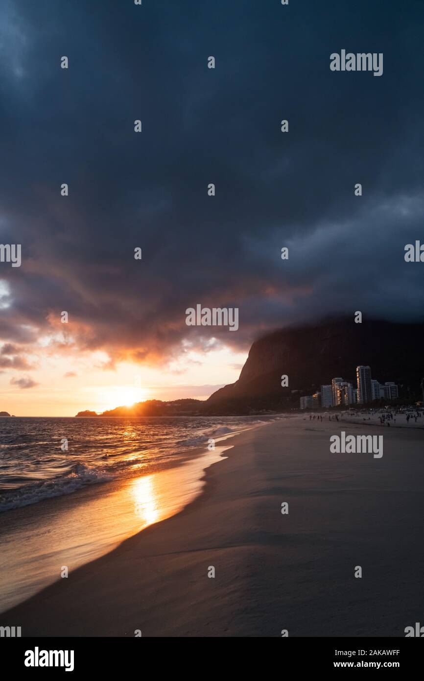 A dramatic sunset with clouds around Pedra da Gavea on Sao Conrado Beach, Rio de Janeiro, Brazil. Stock Photo