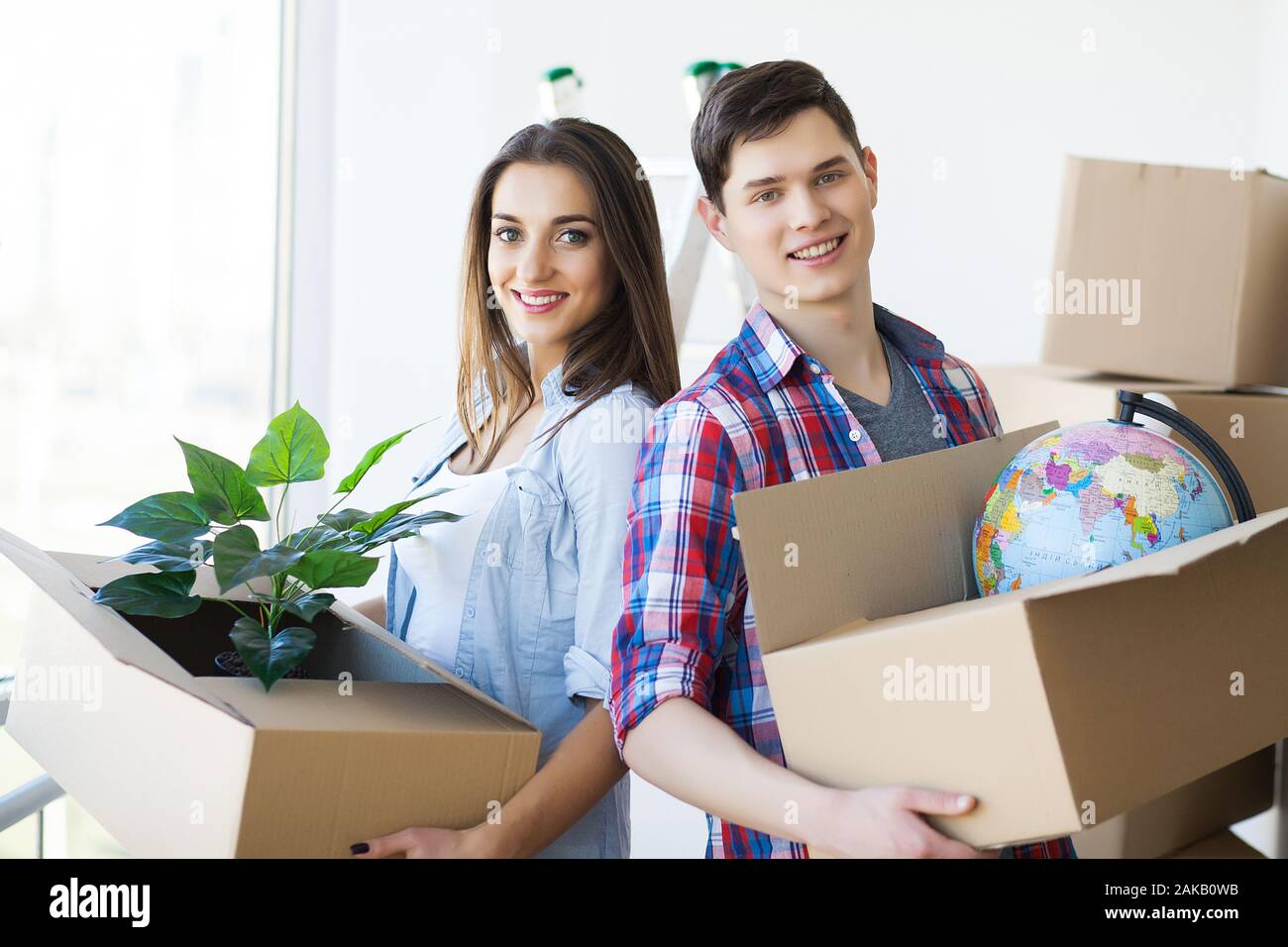 Happy couple with boxes moving to new home Stock Photo - Alamy