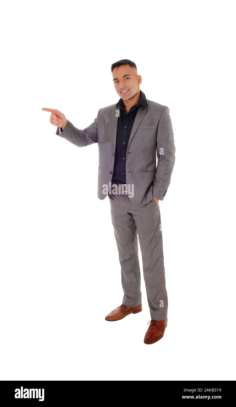 A handsome young man standing with his hands in his pocket in a gray suit, pointing with one hand, isolated for white background Stock Photo