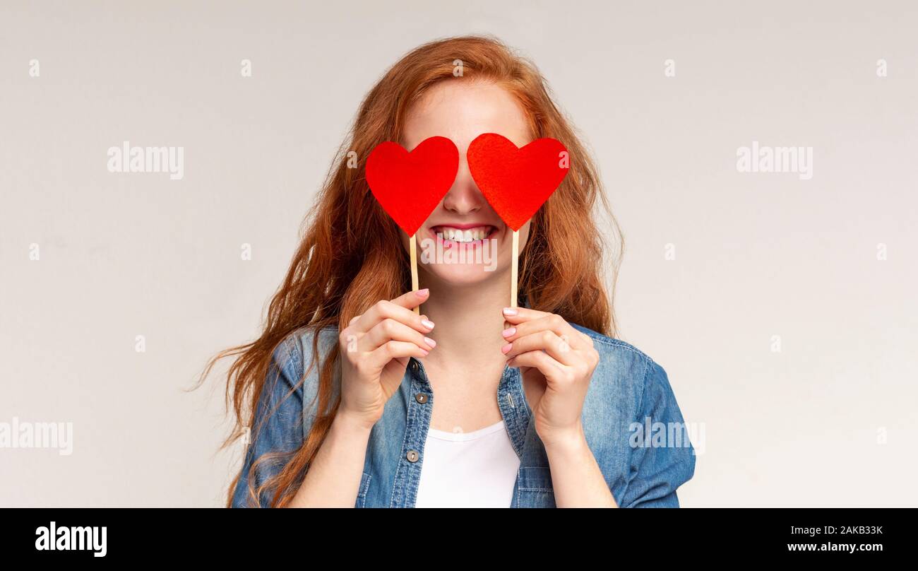 Love is blind. Happy redhead girl covering her eyes with red paper hearts,  panorama with free space Stock Photo - Alamy