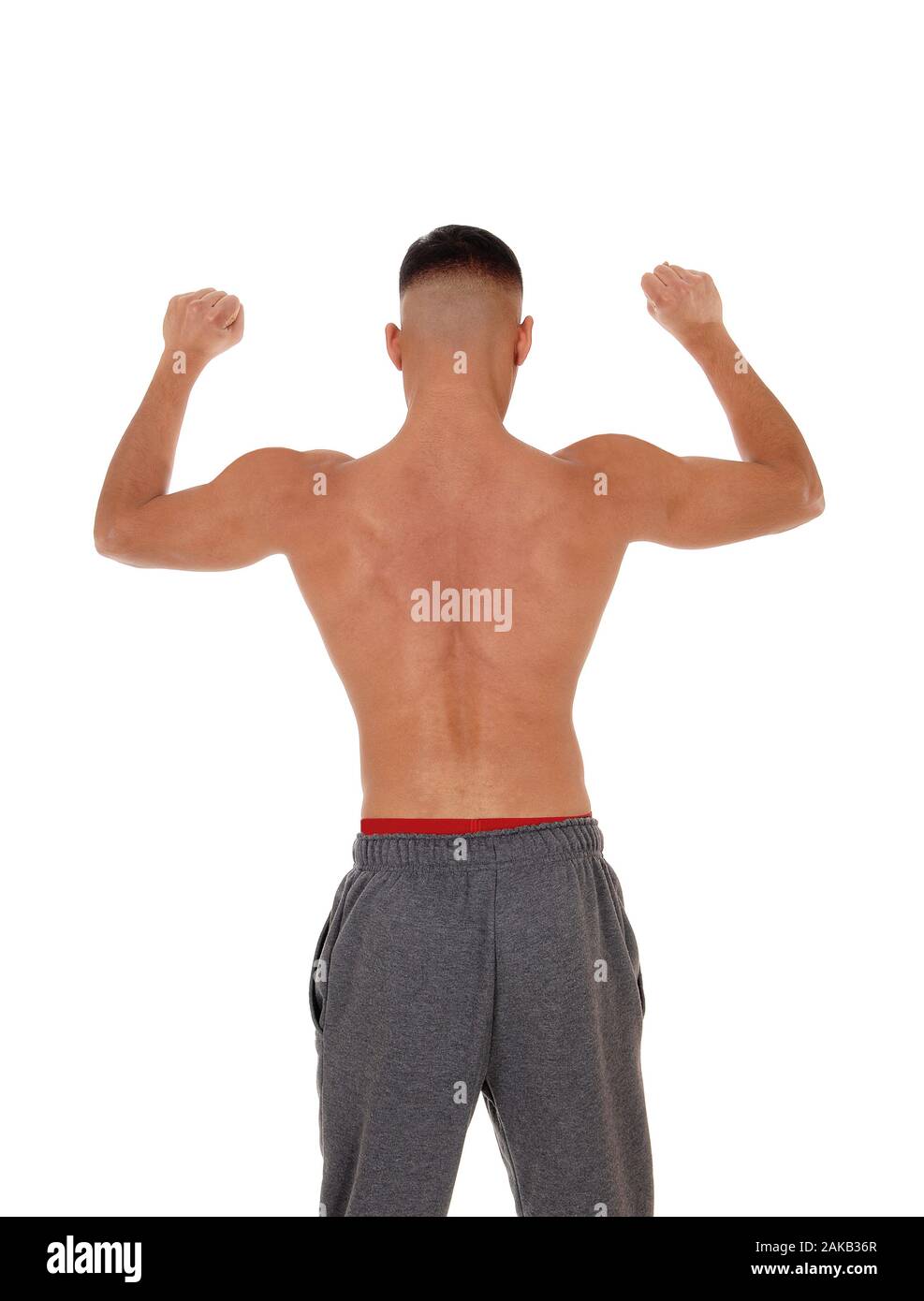 A handsome young east Indian man standing shirtless from the back in track pants with red underwear, isolated for white background Stock Photo