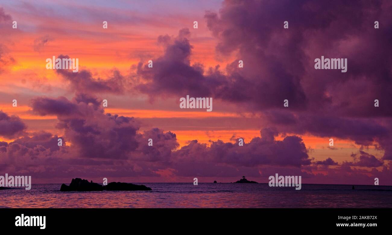 Seascape with rock formations silhouetted under moody sky at sunset, La Digue, Seychelles Stock Photo