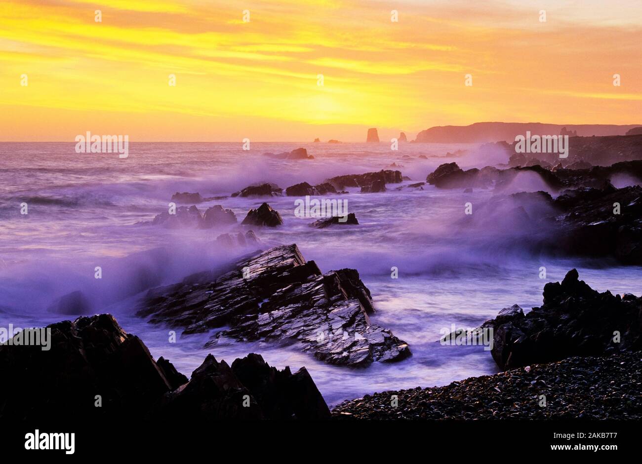 Landscape with waves crashing on rocky coastline at sunset, Newfoundland, Canada Stock Photo