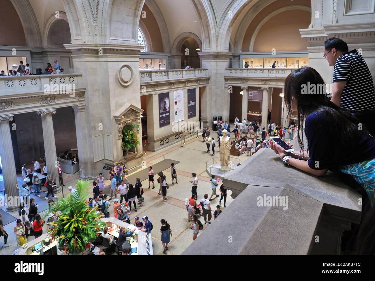 New York City, NY USA. Jul 2017. Asian tourists on second floor looking down on people visiting the Metropolitan Museum of Art. Stock Photo